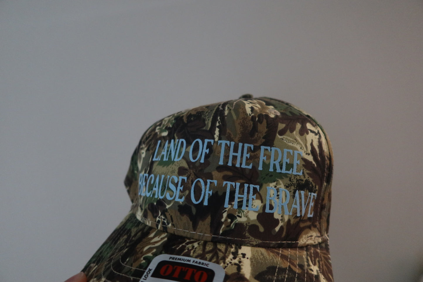 LAND OF THE FREE BECAUSE OF THE BRAVE-CAMO WITH BLUE HAT
